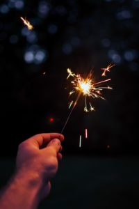 Hand holding a burning sparkler; the Plainfield fireworks celebration is coming up soon.