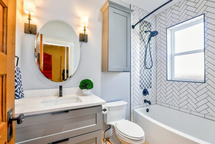 Round mirror in an updated bathroom; mirrors are great home staging accessories to use when selling your home.