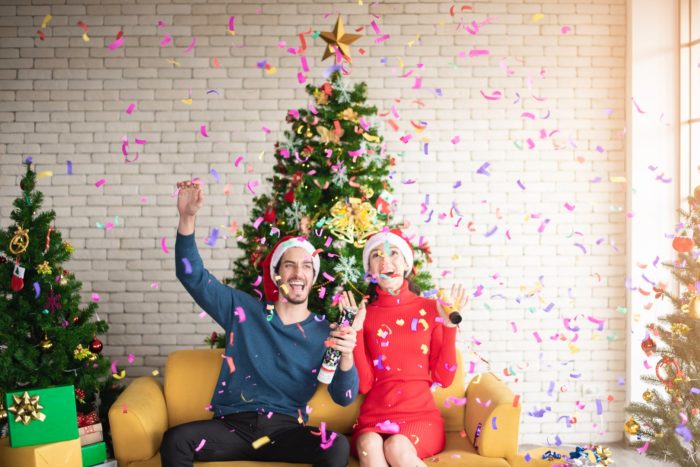 Parents celebrating in front of a Christmas tree; a parents night out is one of the December 2019 events happening.
