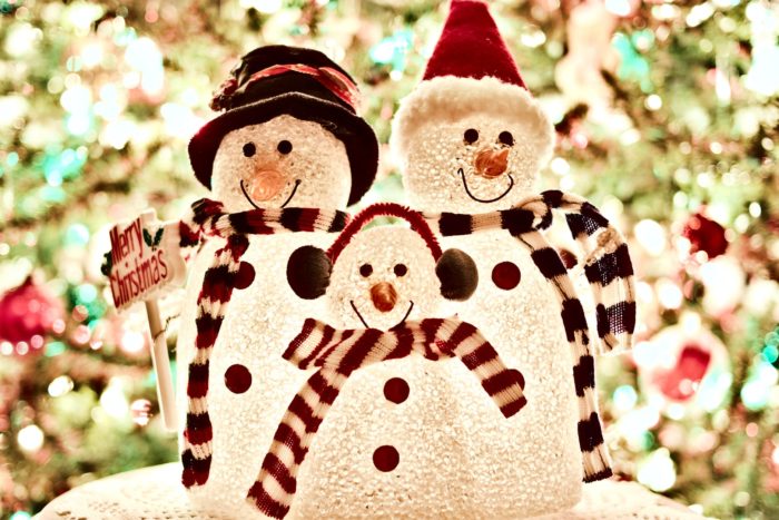 Group of snowmen in front of a Christmas tree; home security during the holidays is vital.