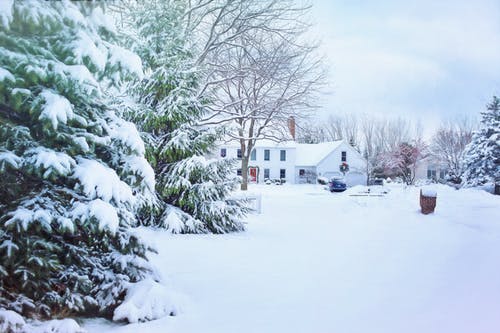 A snow covered house on a large lot; home security during the holidays is so important to consider.