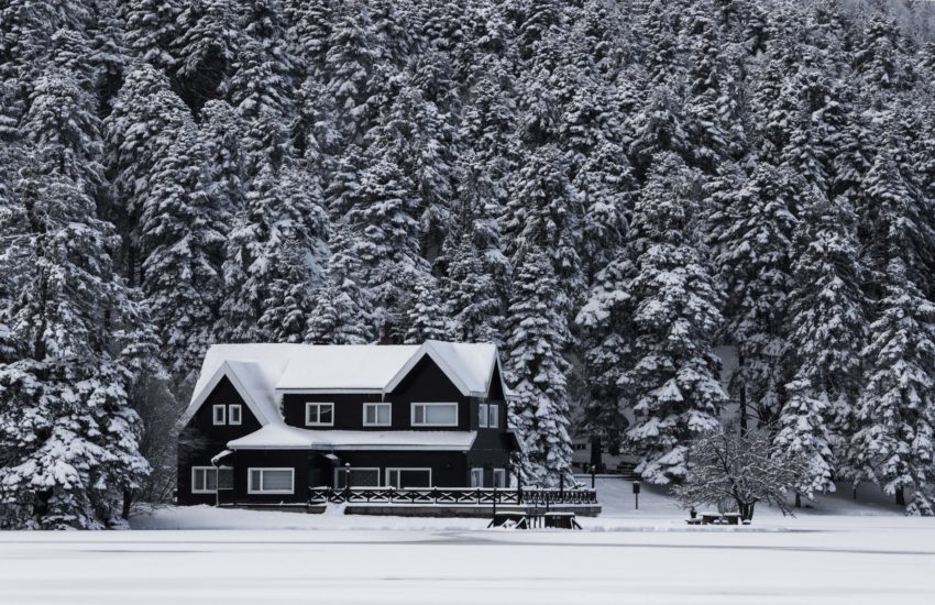 House nestled in a snowy woods; there are a few things to do to get ready to sell in the spring.