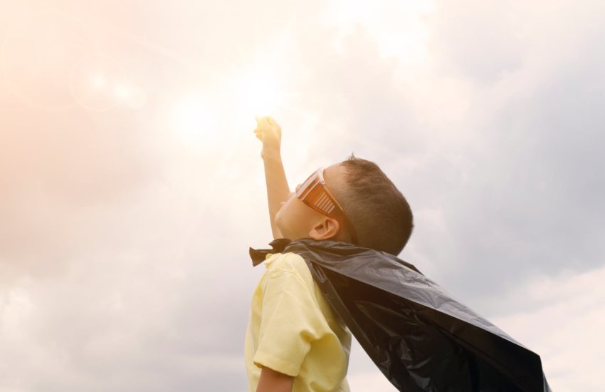 Boy in a super hero cape looking up at the sky; here are the best kid places in the area.