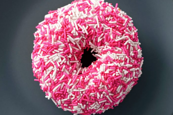 Closeup of a doughnut with pink, red and white sprinkles. 
