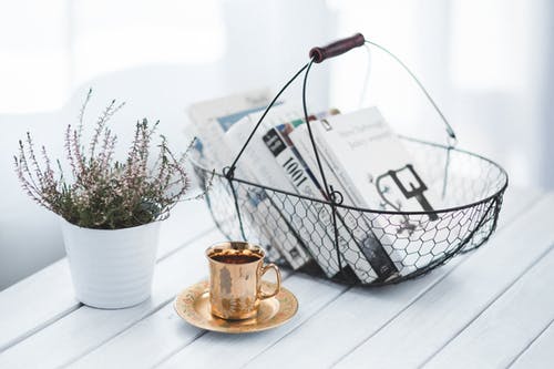 A small vignette with a lavender plant, a cup and saucer and a basket of books; great home staging tips include using vignettes.