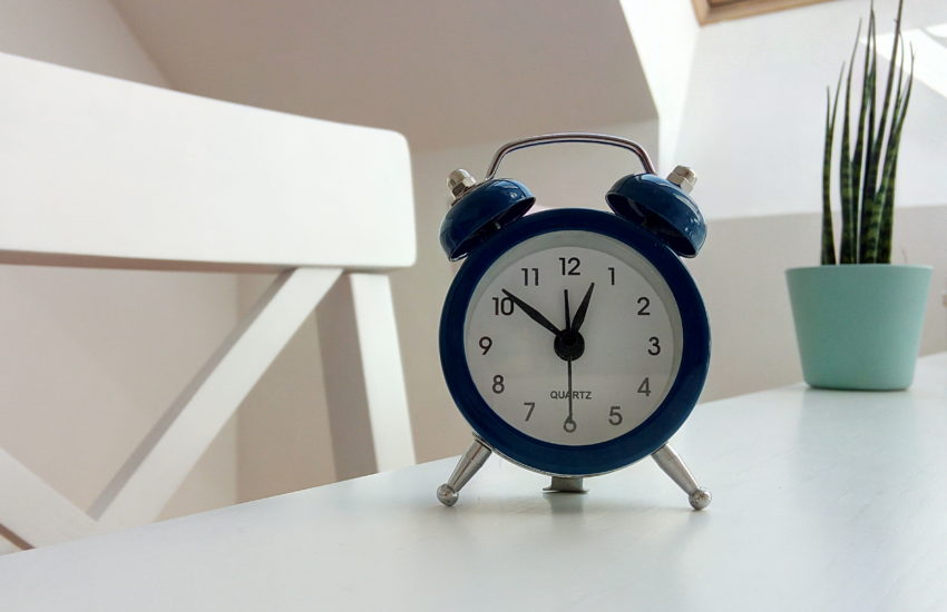 Alarm clock sitting on a white table; now is the time to sell your home!