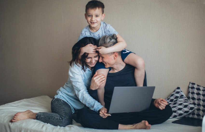 Mother and father working from home on a computer with their child.
