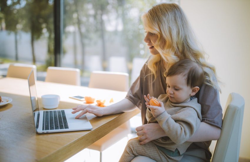 Woman holding a baby on her lap while on the computer.